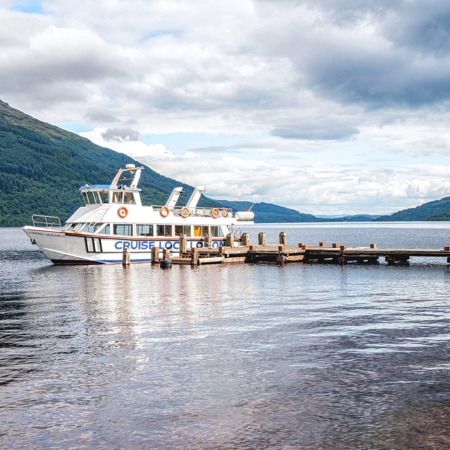 Cruise boat docked at a pier with mountains in the background
