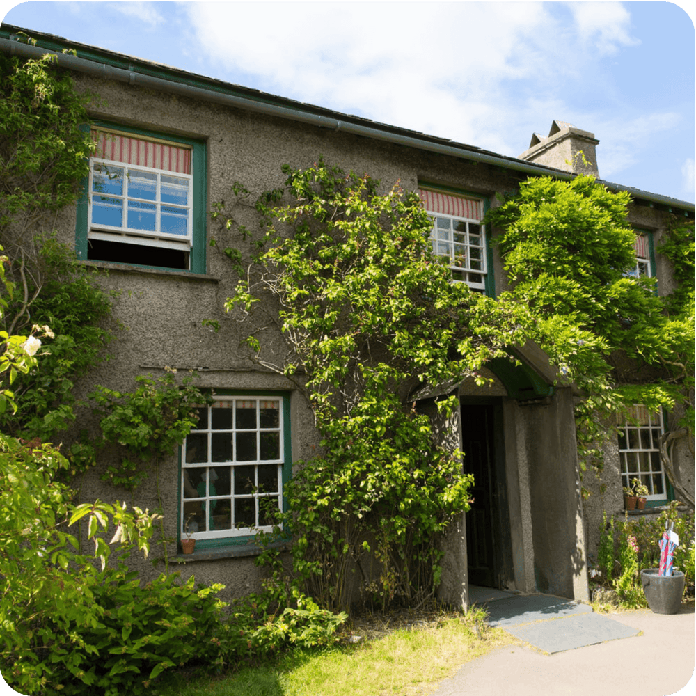
                  
                    Georgian-style house covered in greenery, located in the scenic Lake District, ideal for tours from London.
                  
                