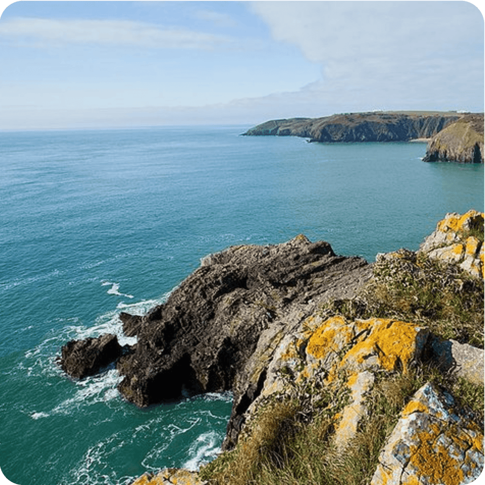 
                  
                    Stunning coastal view from a cliff in Wales, showcasing the rugged landscape and tranquil waters.
                  
                